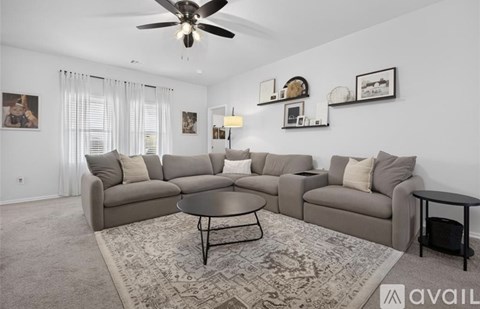 A living room with a grey sectional sofa, a round table, and a ceiling fan.