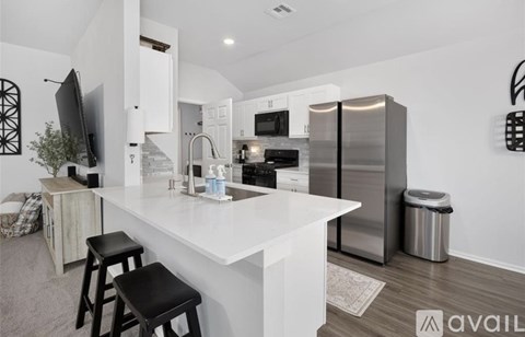 A modern kitchen with a white countertop and stainless steel appliances.