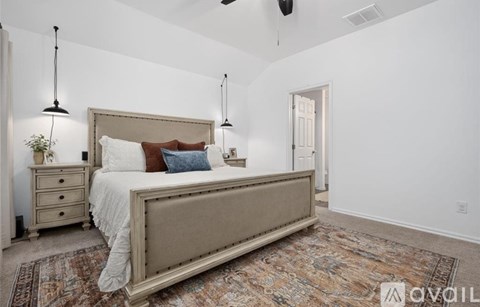 A bedroom with a large bed, a nightstand, and a rug.