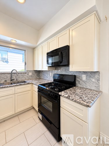 A kitchen with a black stove and microwave above a granite counter.