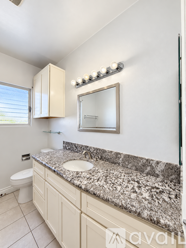 A bathroom with granite countertops and a large mirror.