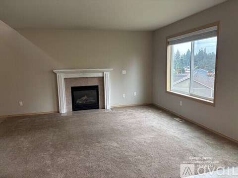 A spacious living room with a fireplace and a large window.