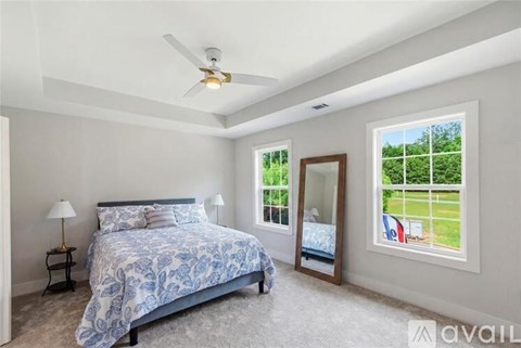 A bedroom with a large bed and a ceiling fan.