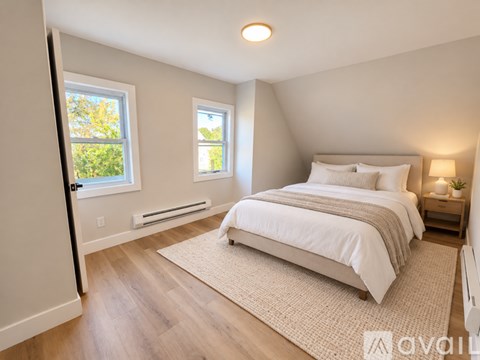 A bedroom with a large bed and two windows.