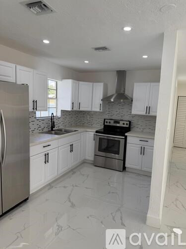 A kitchen with white cabinets and marble flooring.