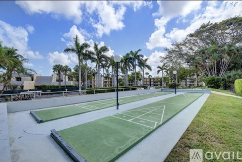 Tennis courts surrounded by palm trees under a blue sky.