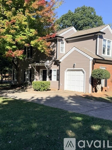 A house with a garage and a tree in front of it.