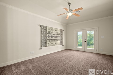 A room with a ceiling fan and a window with a view of trees.