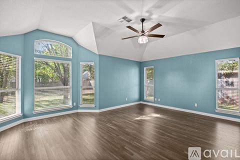 A spacious room with a ceiling fan and large windows.