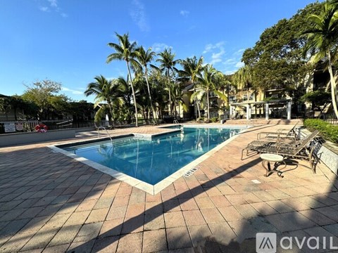 A pool surrounded by palm trees and a patio area.