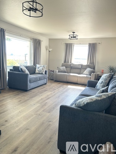 A living room with two grey couches and a wooden floor.