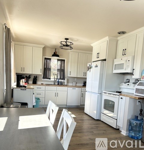 A kitchen with white cabinets and appliances is available for rent.