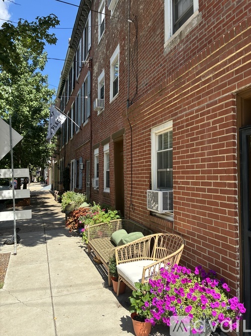 A row of plants in front of a brick building.