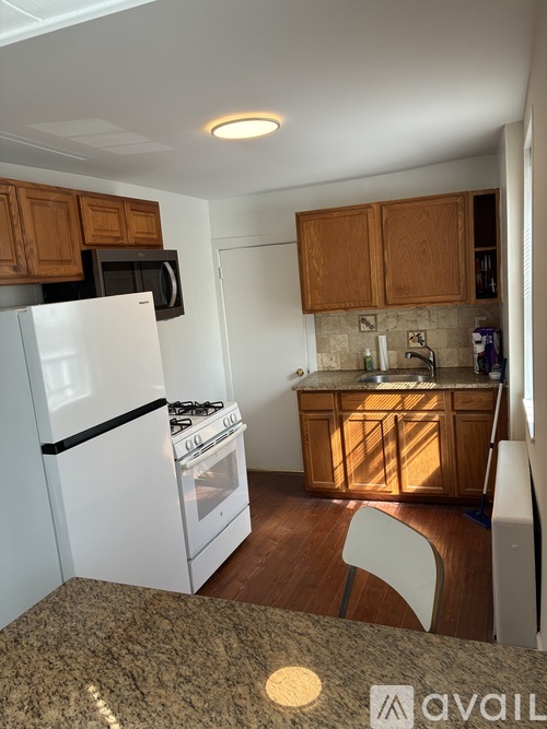 A kitchen with a white refrigerator, white stove, and wooden cabinets.