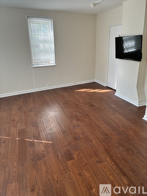 A room with wooden flooring and a television on the wall.