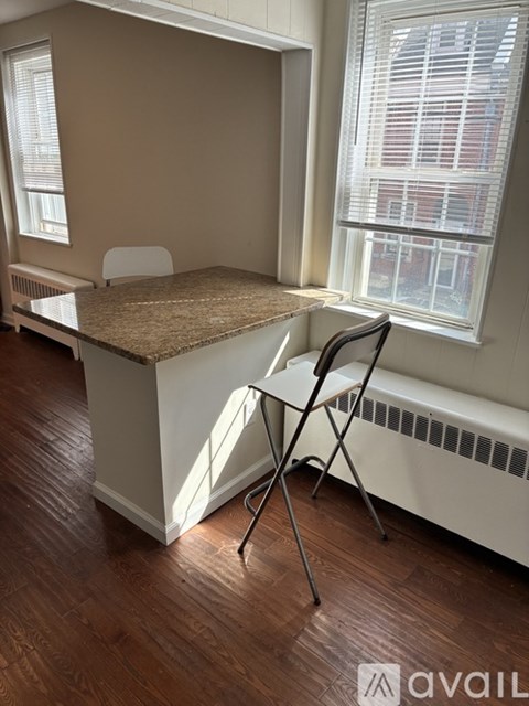 A room with a desk and chair in front of a window.