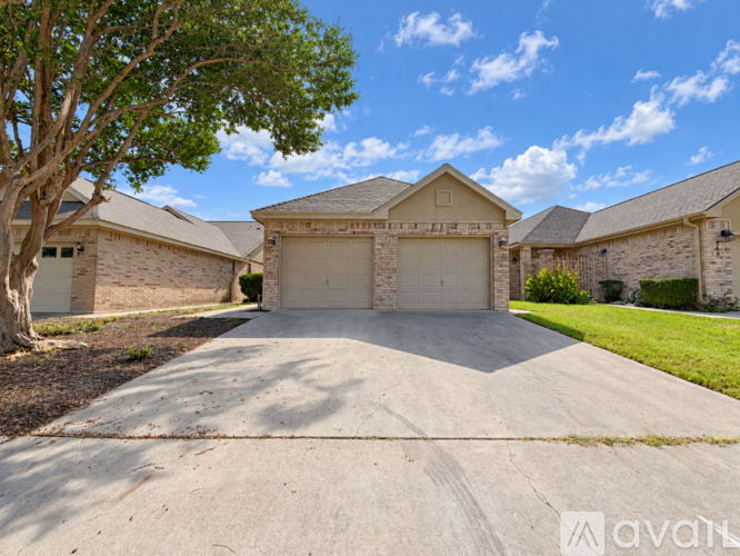 A house with a large driveway and a tree in front.