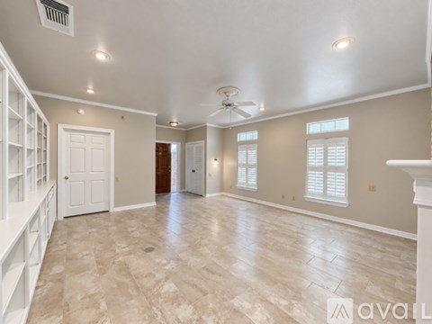A spacious room with a tiled floor and a ceiling fan.