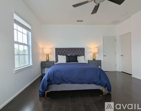 A bedroom with a bed, two lamps, and a ceiling fan.