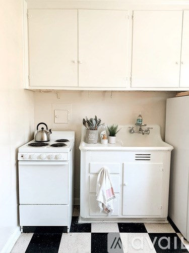 A small white kitchen with a black and white checkered floor.