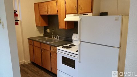 A white refrigerator is in a kitchen with wooden cabinets.