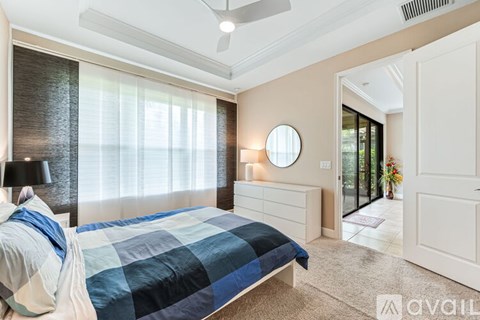 A bedroom with a bed, a ceiling fan, and a round mirror on the wall.