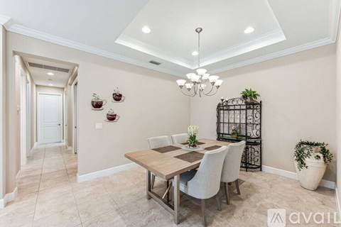 A dining room with a wooden table and chairs, a chandelier, and a potted plant.