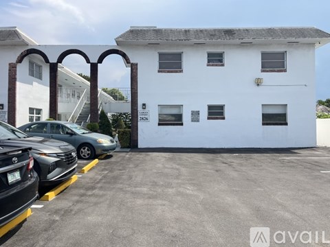 A white building with a parking lot in front of it.