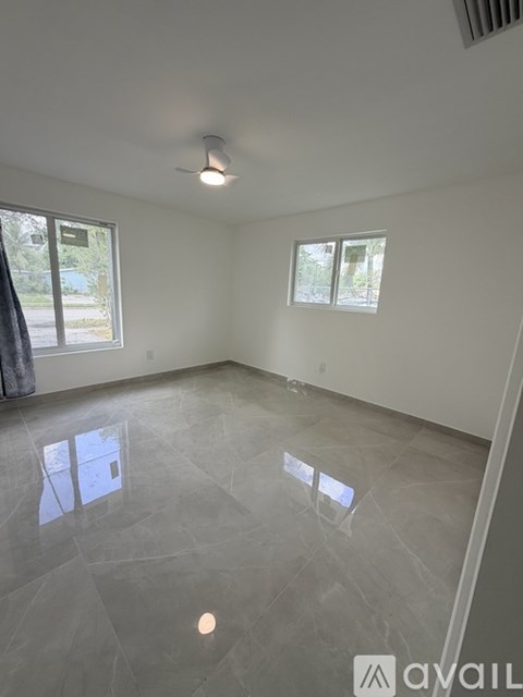 A spacious room with a tiled floor and two windows.