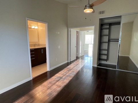 A spacious room with wooden floors and a ceiling fan.