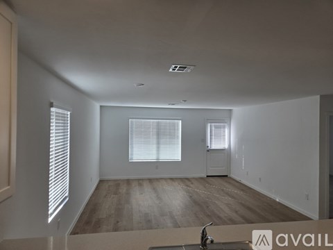A spacious room with wooden flooring and white walls.