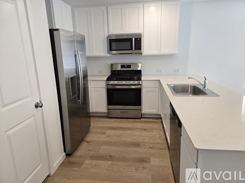 A kitchen with white cabinets and a stainless steel refrigerator.