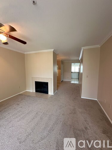A living room with a carpeted floor and a fireplace.