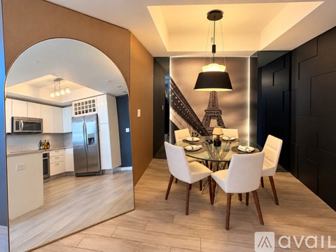 A modern dining room with a glass table and white chairs.