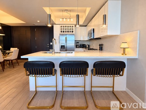 A modern kitchen with a white countertop and black bar stools.