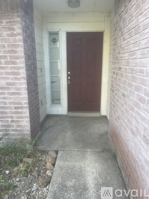 A brown door is at the end of a concrete walkway.