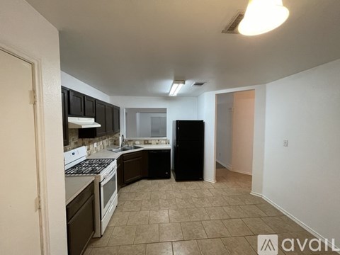 A kitchen with a black refrigerator and white appliances.