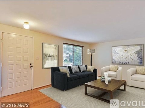 A living room with a black couch, a coffee table, and two chairs.