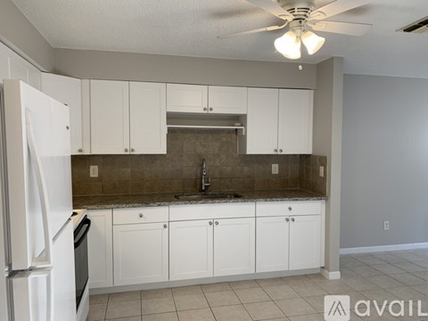 A kitchen with white cabinets and a white refrigerator.