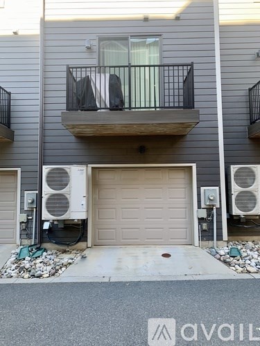 A grey building with a balcony and a garage door.