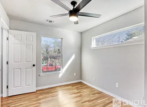 A room with a ceiling fan and a window with a view of trees.