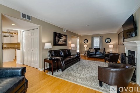 A living room with a black leather couch and a fireplace.