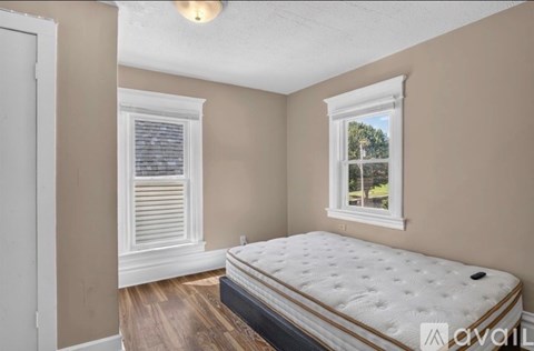 A bedroom with a large bed and a window with blinds.