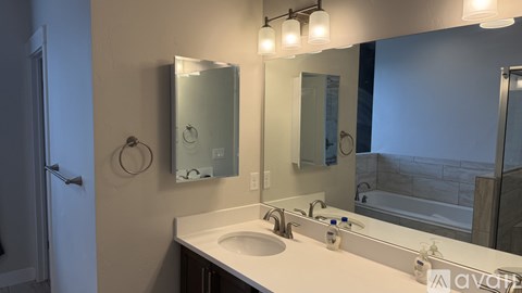 A bathroom with a sink, mirror, and lighting fixtures.