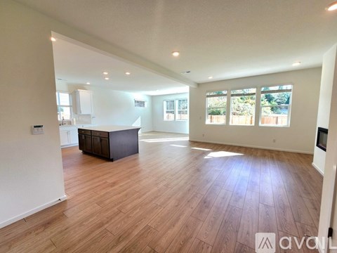 A spacious room with wooden flooring and a large window.
