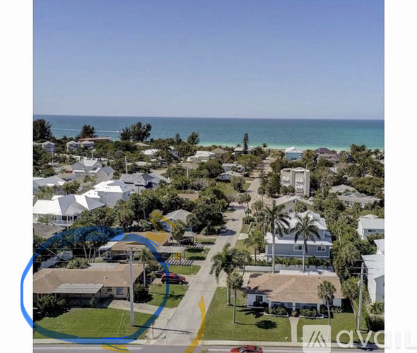 A residential area with a clear blue sky above and a body of water in the distance.