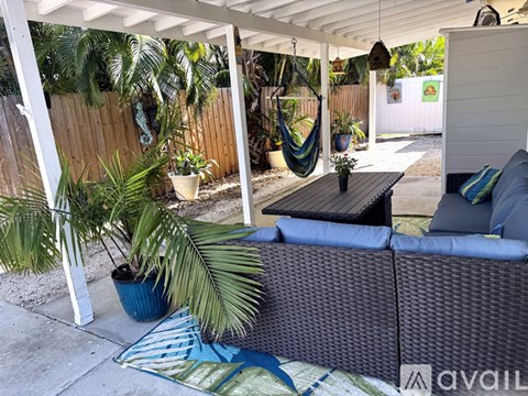 A patio with a couch, a table, and a hammock.