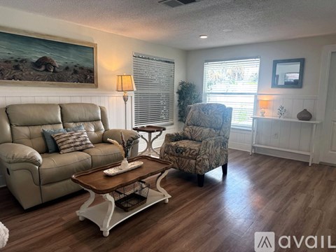 A living room with a tan couch, a chair with a camouflage pattern, and a coffee table with a basket on it.