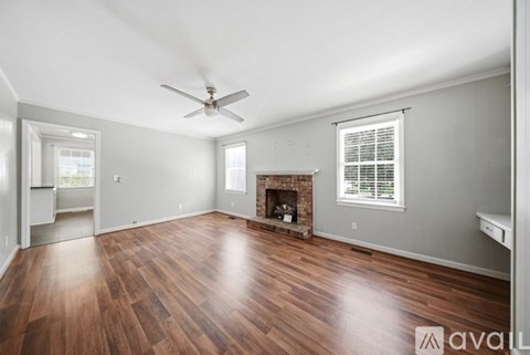 A spacious living room with wood flooring and a fireplace.