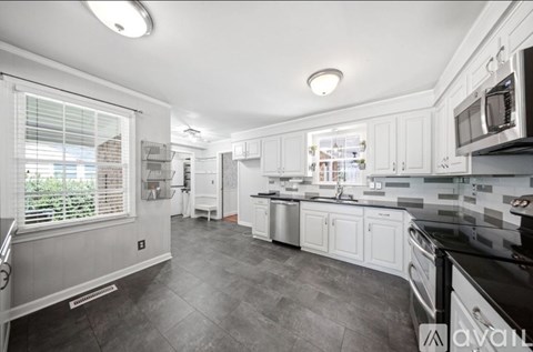 A modern kitchen with white cabinets and black countertops.